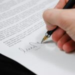 Close-up of a hand signing a legal document with a fountain pen, symbolizing signature and agreement.